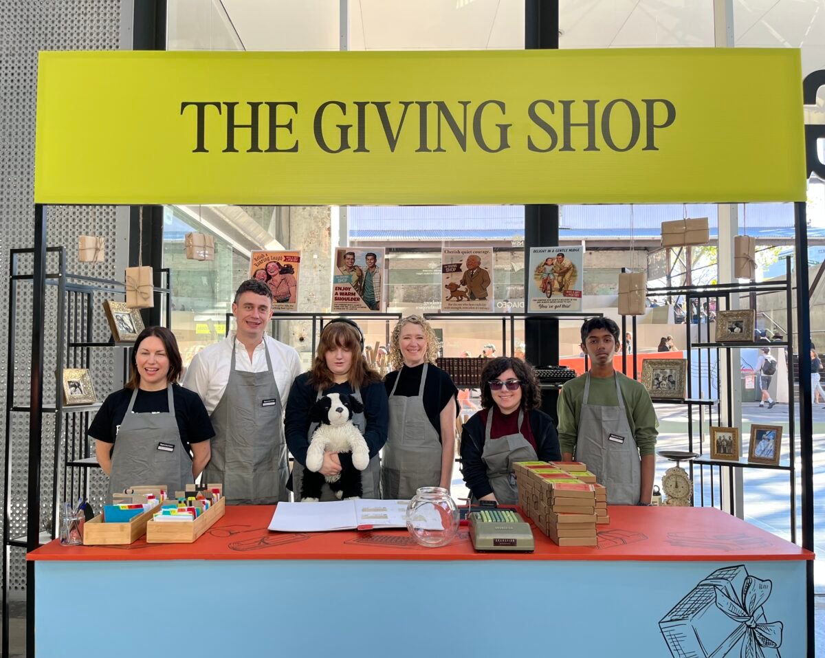 Students and Story Factory staff at The Giving Shop, a brightly decorated stall with posters and hanging gifts
